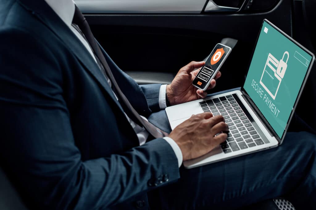 man on laptop using phone to ensure data is secure