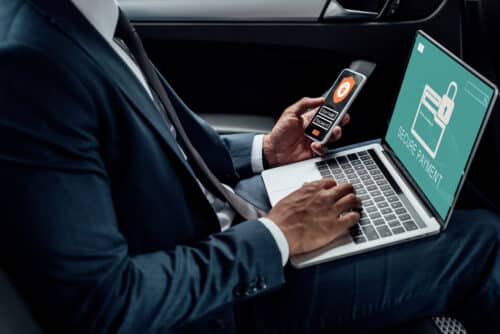 man on laptop using phone to ensure data is secure