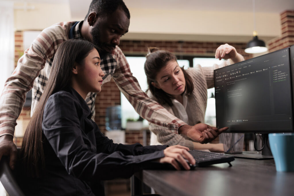 team looking at computer discussing cybersecurity compliance