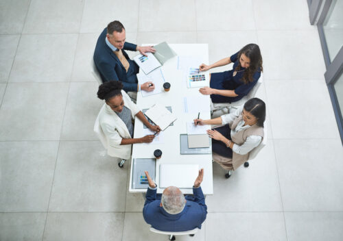 employees sit around a table with graphs and charts discussing something
